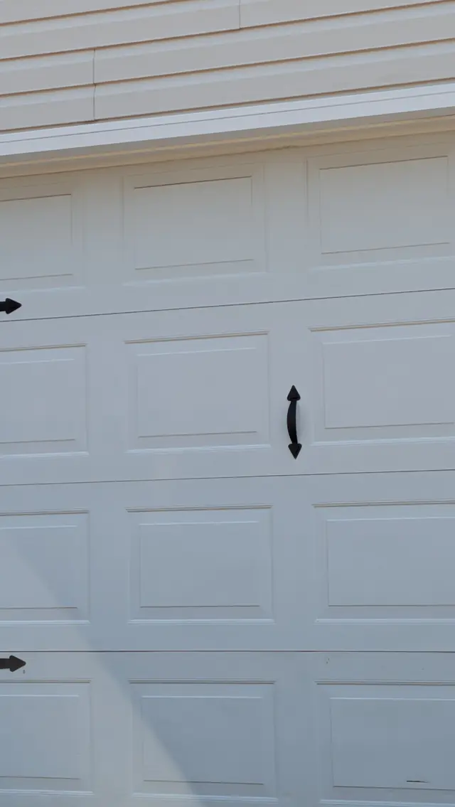 White carriage-style garage door with decorative black handles