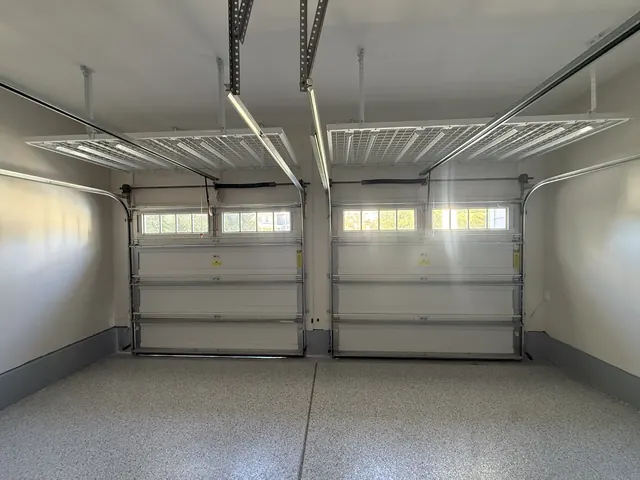 Two sectional garage doors with torsion springs mounted above them, seen from inside a two-car garage